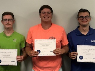 Three young men showing off certificates