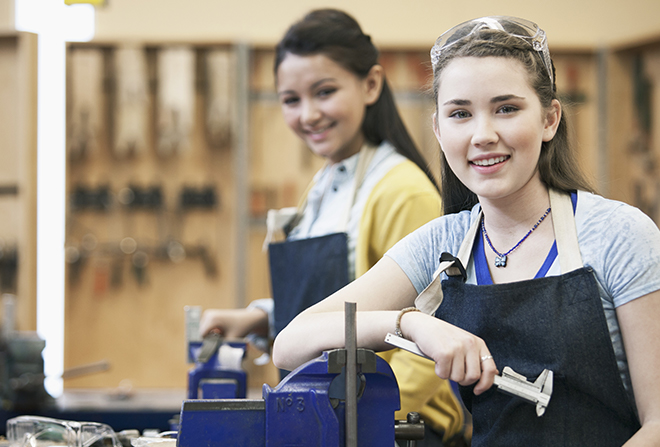 Two young women looking at camera with tools in hand