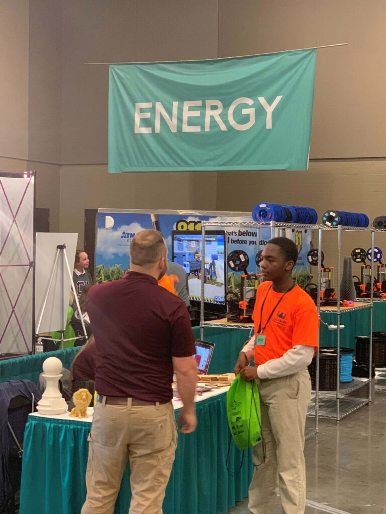 Young man talking to man at a booth in Energy area