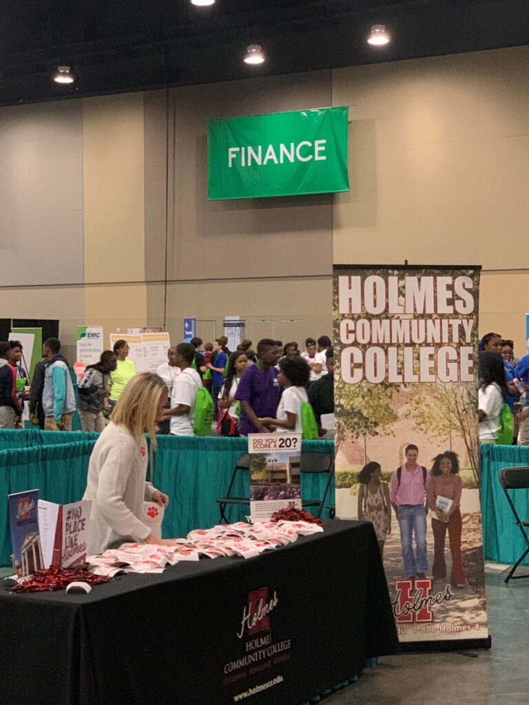 Holmes Community College booth in foreground with young adults in background