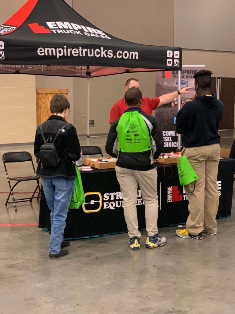Three young adults visiting a Empire Truck Sales booth